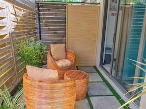 A corner with two wicker chairs, a wooden door, and a glass door. - The nice corner (Grand baie)