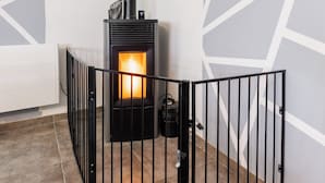 Un interior moderno con una estufa de leña, una verja de metal negro y un reloj de pared.