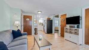 Una sala de estar con un sofá, una mesa de centro y un televisor sobre un mueble.