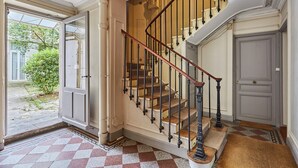 A grand staircase with a wooden handrail and black balusters, leading to an upper floor. - Superb Apartment Sacre Coeur With Air-conditionner (Paris)