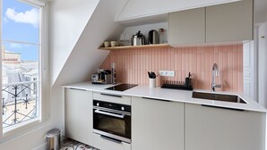 A modern kitchen with a built-in oven, a sink, and a window overlooking a cityscape. - Superb Apartment Sacre Coeur With Air-conditionner (Paris)