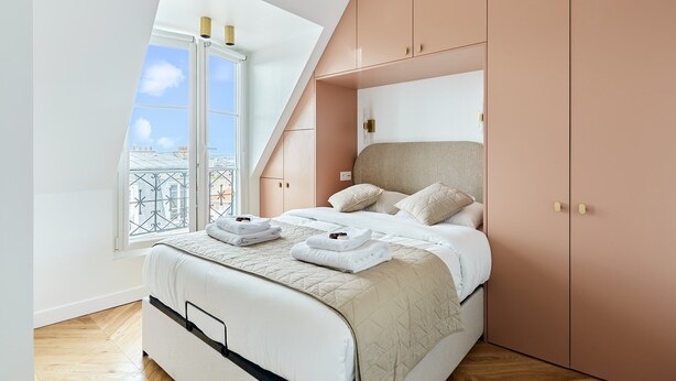 A modern bedroom with a large bed, a skylight, and a view of the city. - Superb Apartment Sacre Coeur With Air-conditionner (Paris)