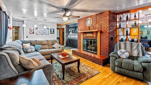 A spacious living room with a brick fireplace, a sofa set, and a coffee table. - Charming 3-bedroom 5 Bed house with WiFi & extras in delightful Geneva (Geneva)