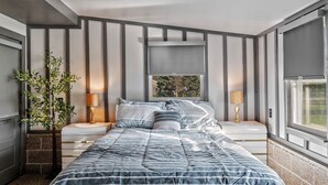 A modern bedroom with a bed, bedside tables, a lamp, and a window. - Charming 3-bedroom 5 Bed house with WiFi & extras in delightful Geneva (Geneva)