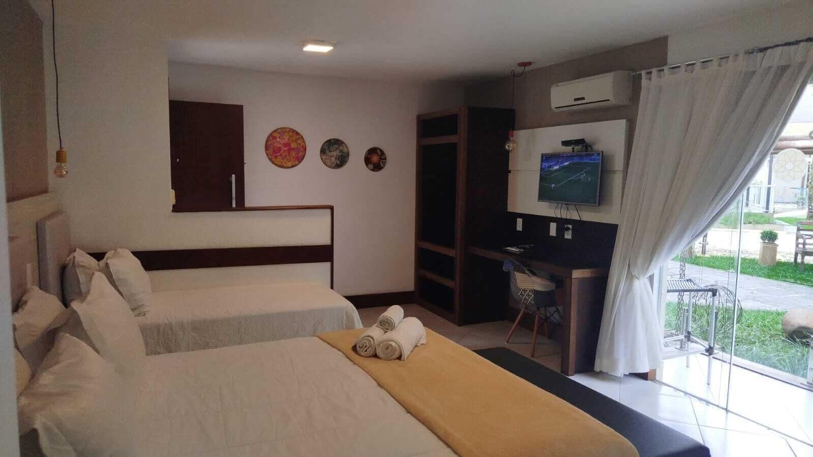 Een hotelkamer met twee bedden, een bureau, een televisie en uitzicht op de omgeving.