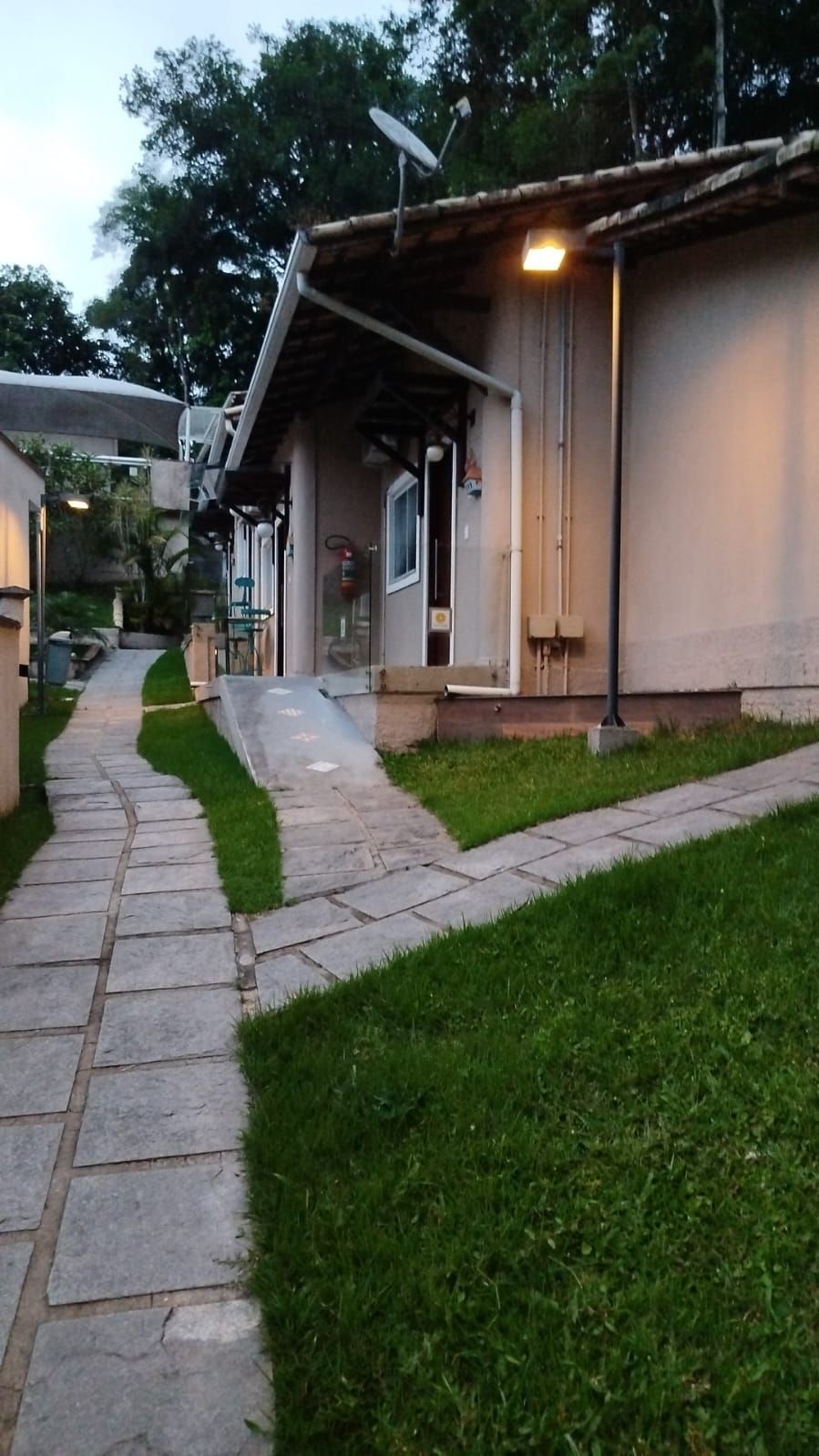 A pathway leading to a building with a covered entrance, a satellite dish, and a fire extinguisher visible.