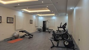 Ein modernes Fitnessstudio mit verschiedenen Trainingsgeräten, darunter ein Rudergerät, eine Gewichtbank und Gymnastikbälle.