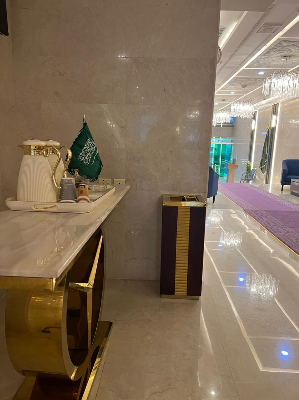 En moderne hotellobby med en receptionsdisk i marmor, en skraldespand og et område med lilla tæppe.