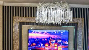 Una sala de estar moderna con un televisor de pantalla plana grande montado en una pared, una araña y un sillón amarillo.