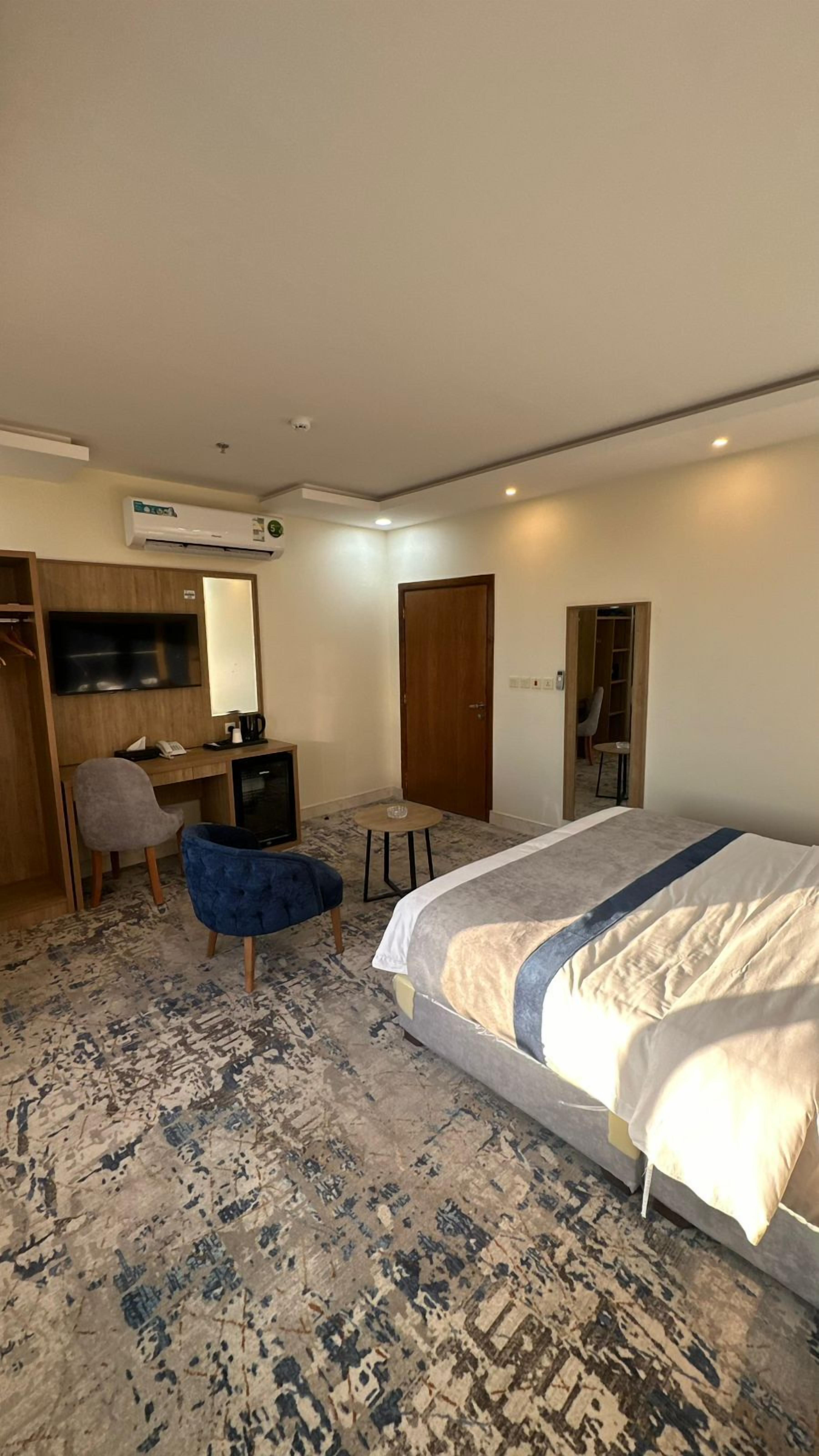 Ein Hotelzimmer mit Bett, Schreibtisch mit Stuhl, einem kleinen Tisch, einer Klimaanlage und einem Kleiderschrank.
