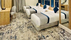 Ein Hotelzimmer mit zwei Betten, einem Schreibtisch, einem Stuhl, einem Spiegel und einem großen Fenster mit Vorhängen.