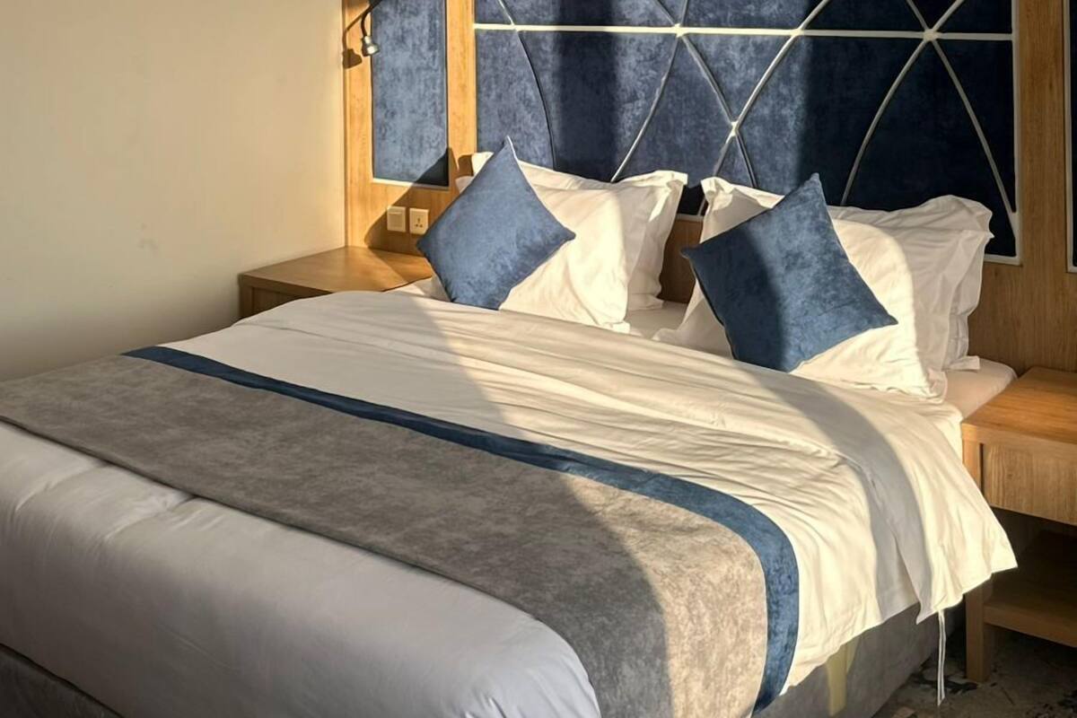 A hotel room with a large bed, a wooden headboard, and a nightstand.