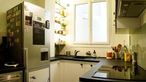 A compact kitchen with a refrigerator, a built-in oven, a sink, and a window above the sink.