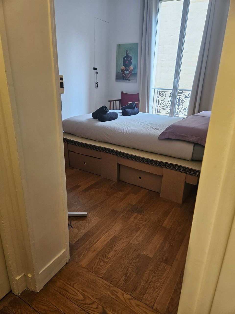 Un dormitorio con cama, un escritorio pequeño, una silla, un ventanal y una puerta.