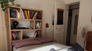 A bedroom with a bed, a bookshelf, a radiator, and a door.