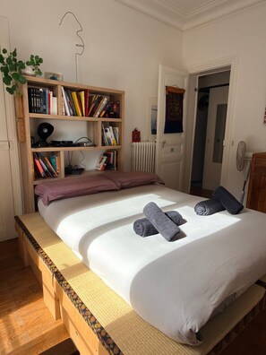 Un dormitorio con cama, estantería, radiador y puerta.