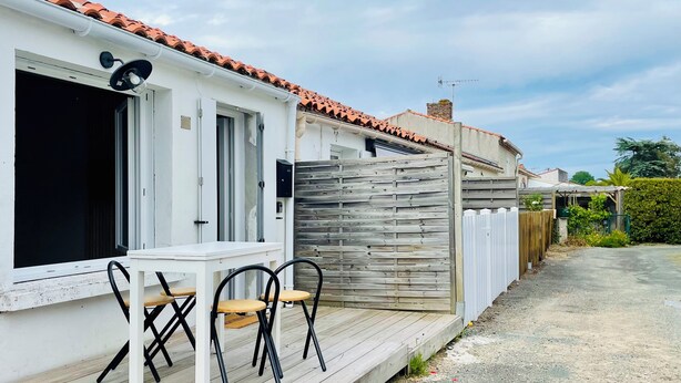 A single-story house with a wooden deck, a white exterior, and a tiled roof. - Cocooning cottage by the sea  (Longeville-sur-Mer)