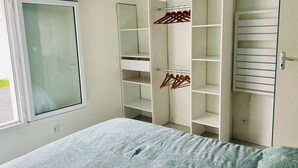 A bedroom with a bed, a wardrobe with multiple shelves, and a window. - Cocooning cottage by the sea  (Longeville-sur-Mer)