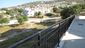 A residential area with houses, a hill in the background, and a fenced pathway. - Peyia, near Paphos, Cyprus - beautiful villa with panoramic view over coral bay  (Peyia)