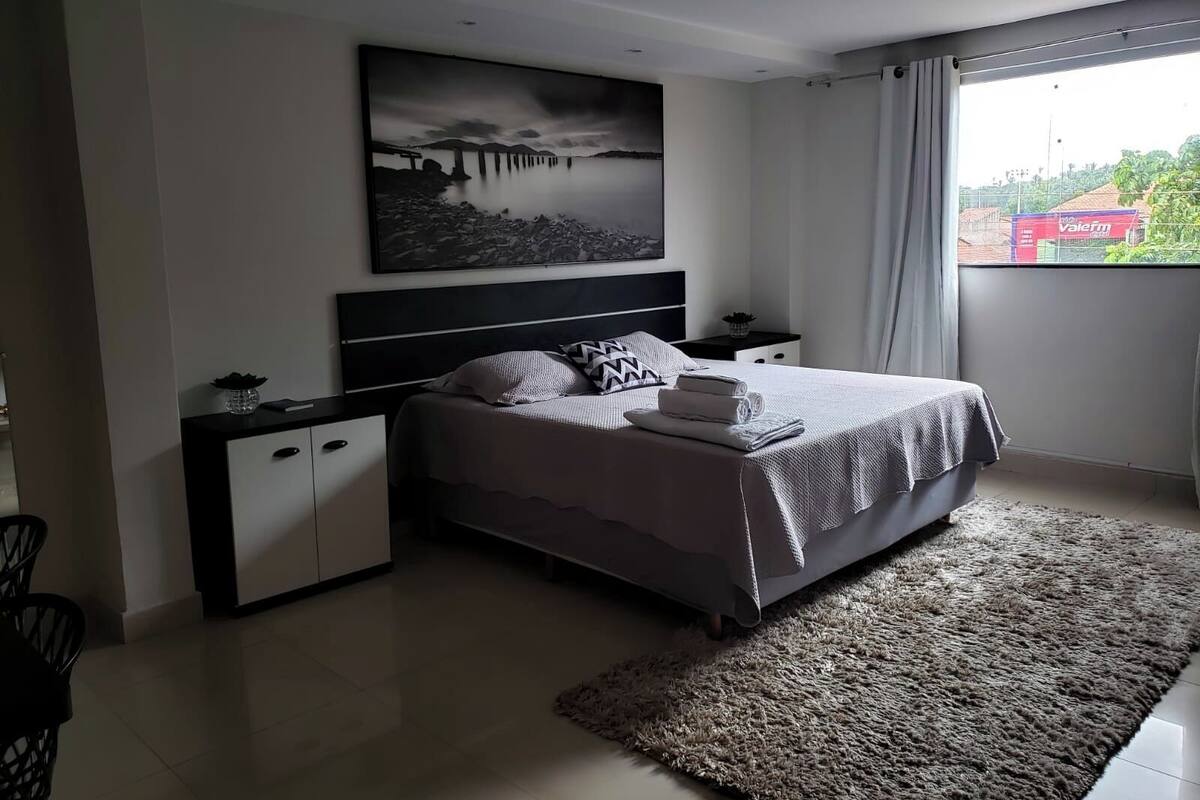 Ein modernes Schlafzimmer mit einem großen Bett, einem Nachttisch, einer Kommode, einem Teppich und einem Bild einer Brücke.