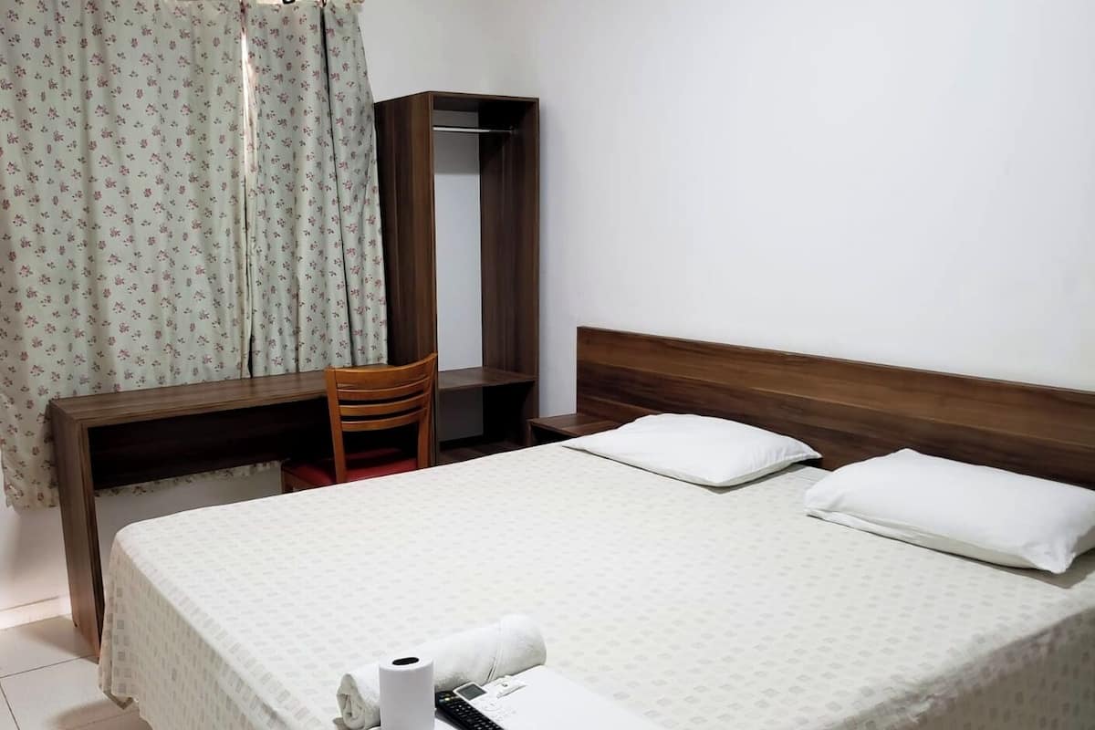 Ein Hotelzimmer mit Bett, Schreibtisch, Stuhl und Kleiderschrank.