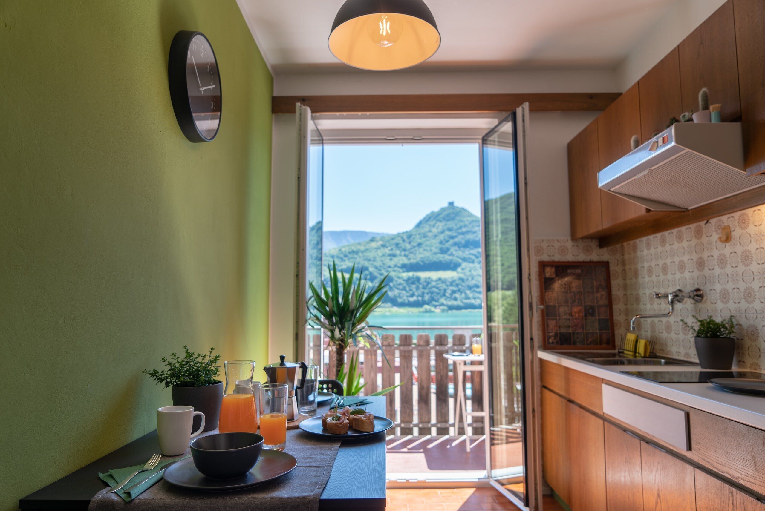 A kitchen with a view of a mountain and a table set with breakfast.