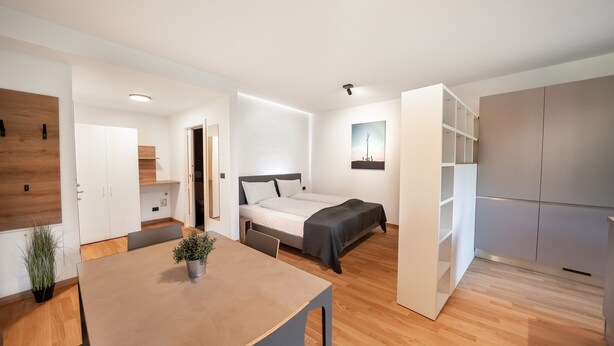 A modern, well-lit bedroom with a bed, bedside table, and a small bedside lamp.