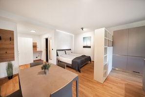A modern, well-lit bedroom with a bed, bedside table, and a small bedside lamp.