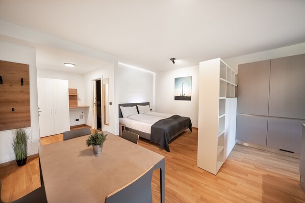 A modern, well-lit bedroom with a bed, bedside table, and a small bedside lamp.