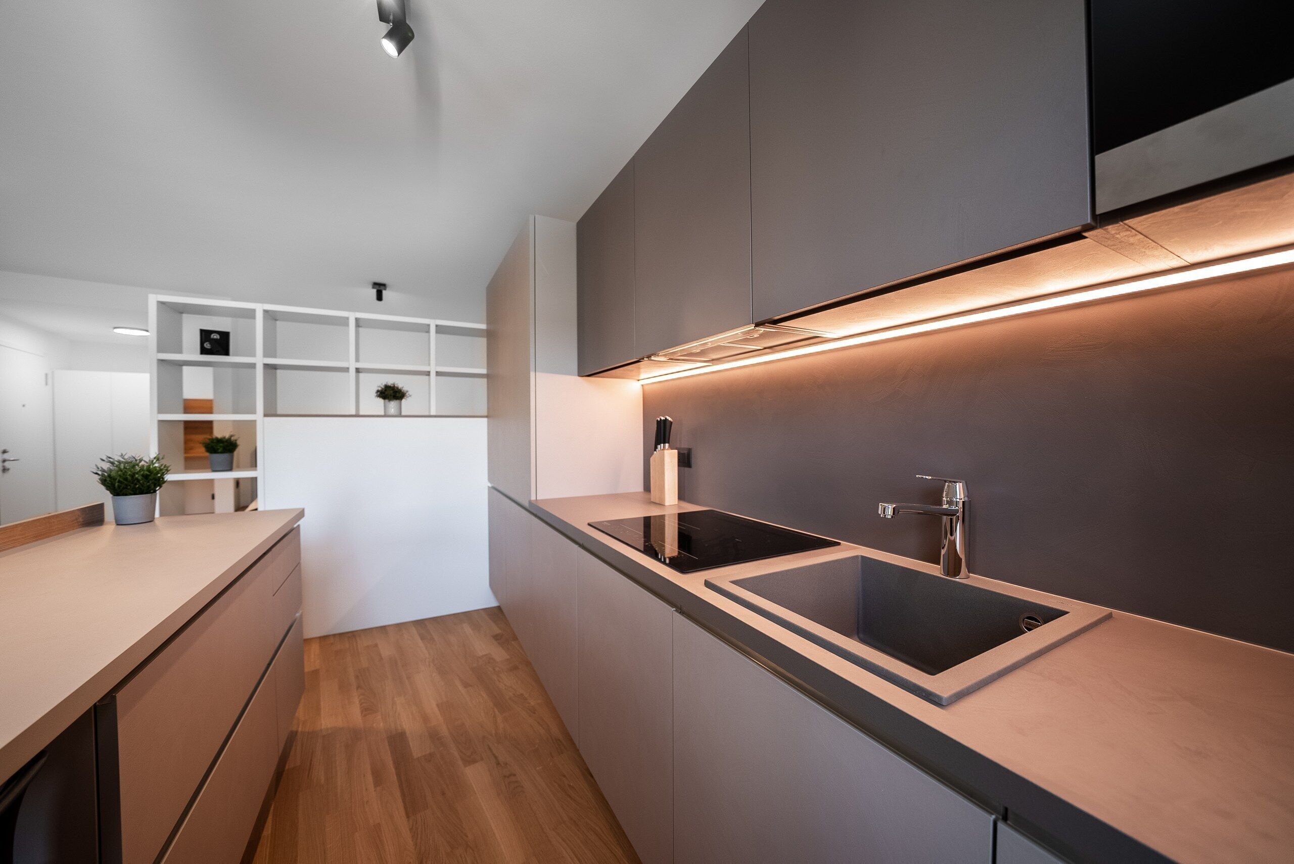 Una cocina moderna con una encimera negra elegante, un horno empotrado y un grifo de acero inoxidable.