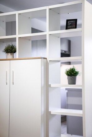 A white wardrobe with two doors and a shelving unit with multiple compartments.