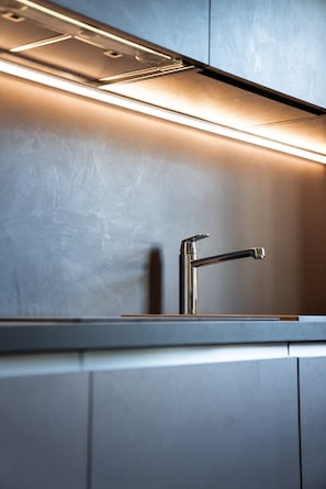 Een moderne keuken met een roestvrijstalen kraan en verlichting onder de keukenkastjes.