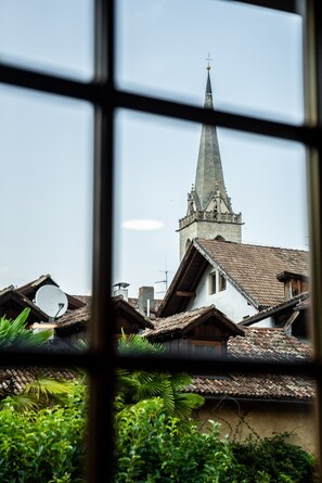Vista a través de una ventana que muestra un campanario de iglesia en el fondo.