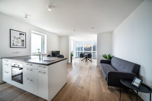 Una cocina moderna con una isla central, un comedor con mesa y sillas, y un sofá gris.