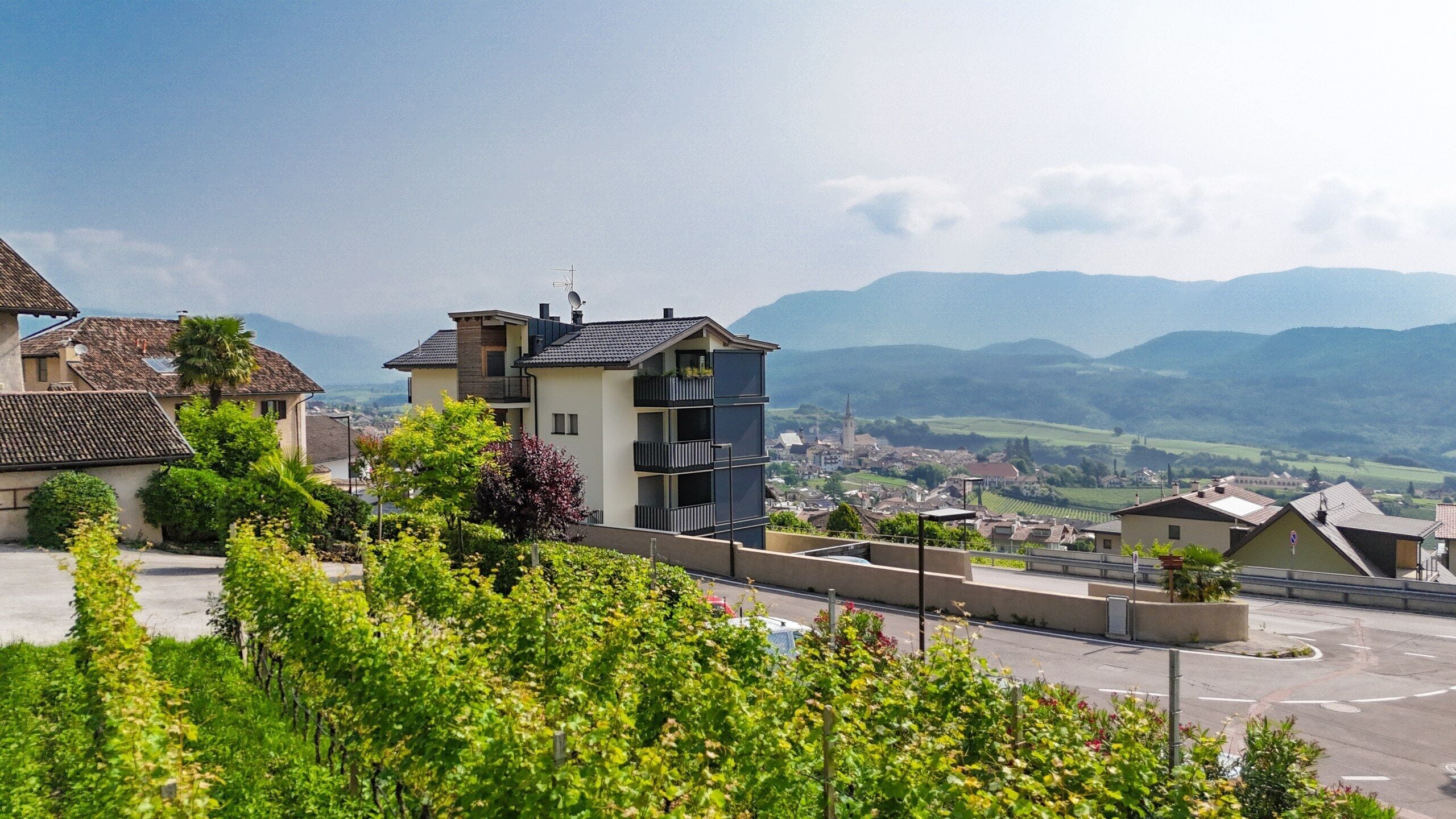 A residential area with modern buildings, a road, and a view of distant mountains.