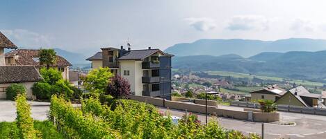 A residential area with modern buildings, a road, and a view of distant mountains.