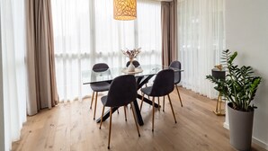 Un coin repas avec une table en verre, des chaises noires, un vase de fleurs et un luminaire suspendu.