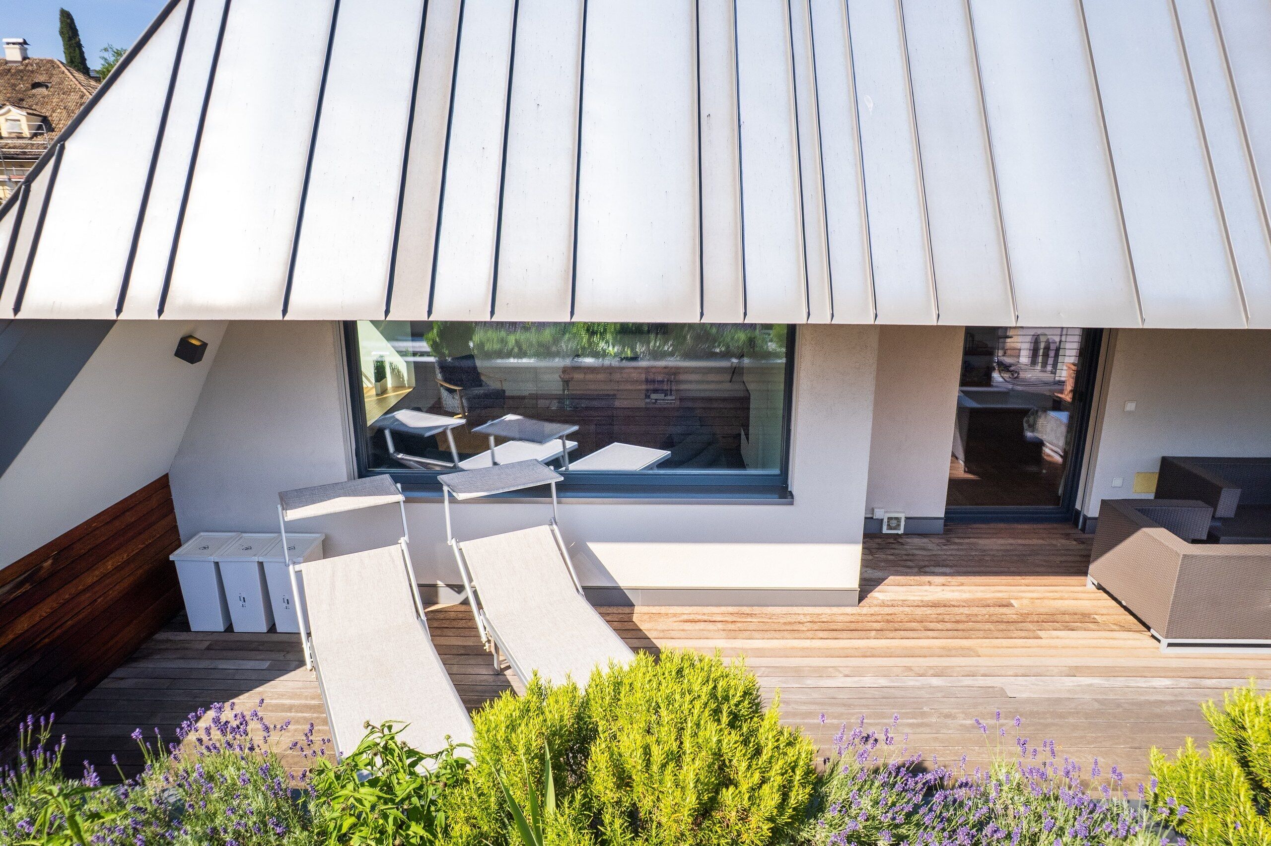 A modern outdoor seating area with lounge chairs and a wooden deck.