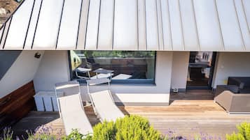 Un espace extérieur moderne aménagé avec des fauteuils confortables et une terrasse en bois.