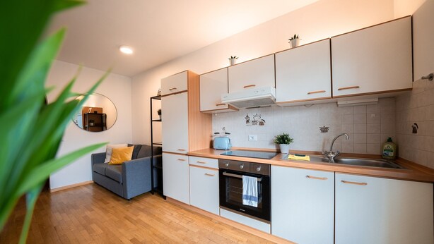 A modern kitchen with white cabinets, a black oven, and a wooden countertop.