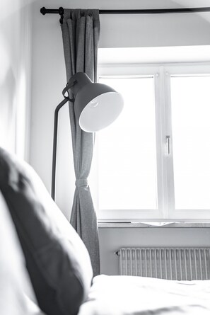 Une pièce avec un lit, une fenêtre avec des rideaux et un lampadaire.