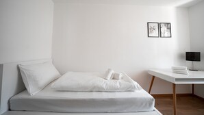 Habitación de hotel minimalista con cama, escritorio y lámpara.