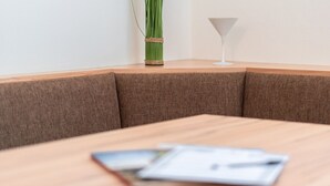 Una mesa de conferencias con un documento, un florero con plantas verdes y un vaso sobre la mesa.