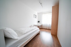 Un dormitorio minimalista con una cama individual, un escritorio y un armario.