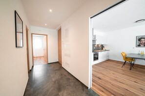 Una cocina moderna con armarios blancos, encimera de madera y una silla amarilla.