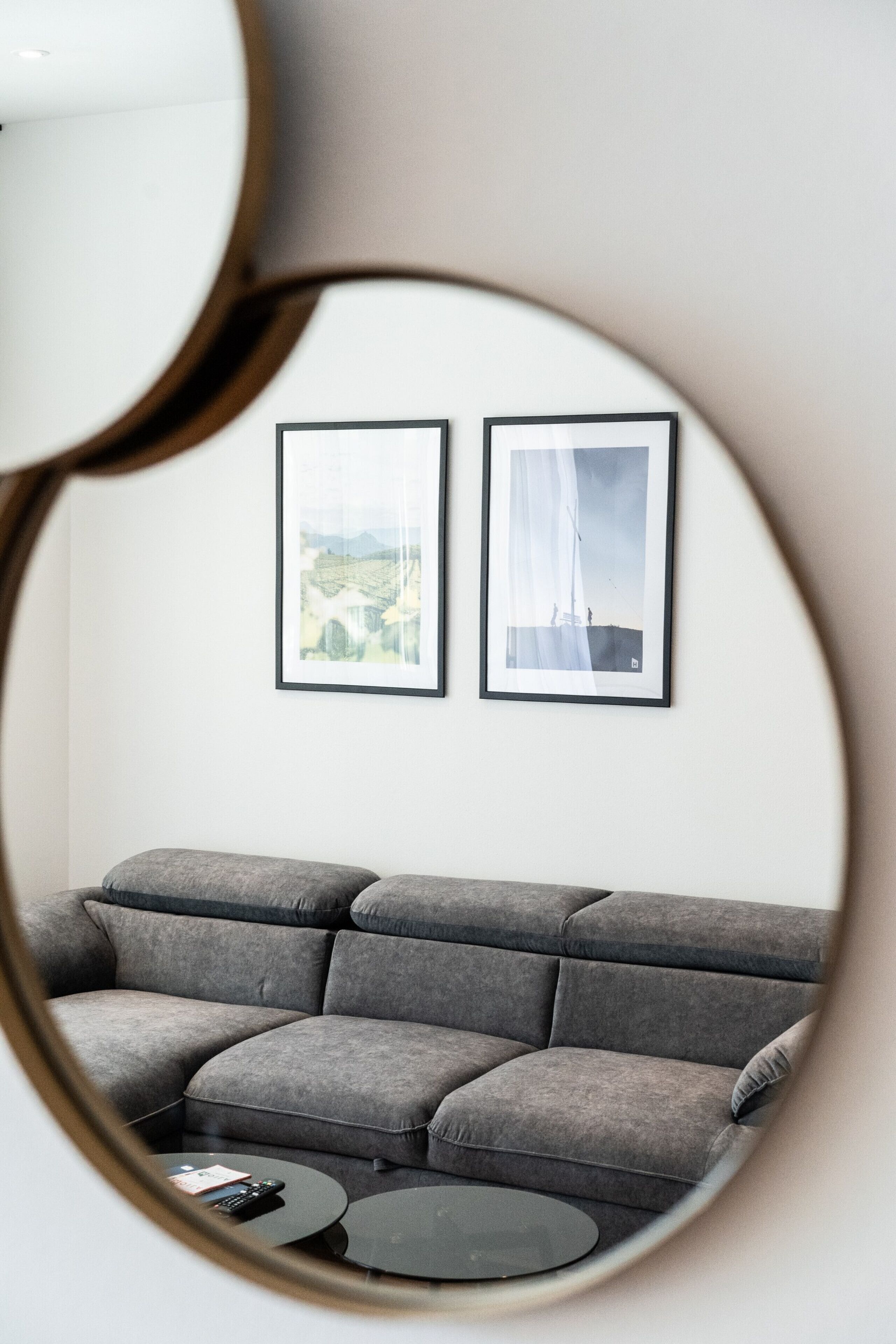 Una sala moderna con un sofá gris, una mesa de centro y dos cuadros en la pared.