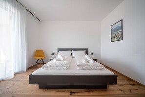 Un dormitorio moderno con una cama grande, una silla y un cuadro en la pared.