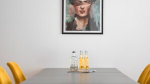 Ein Essbereich mit einem Tisch, zwei gelben Stühlen und einem gerahmten Kunstwerk an der Wand.