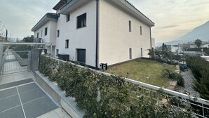 A modern two-story house with a flat roof, a small front yard, and a metal fence.