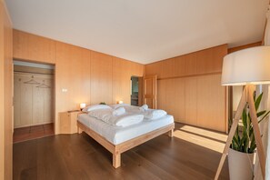 Un dormitorio moderno con cama de madera, lámparas de noche y vista al baño.